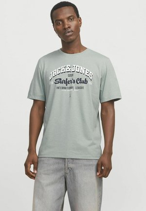 Lichtgroene t-shirt met een ronde halslijn. Bevat de tekst "JACK&JONES Surfer's Club" in marineblauw en wit. Korte mouwen, relaxte pasvorm.