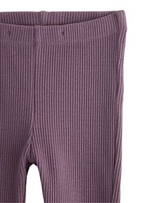 Nærbillede af ribbet, lilla stofbukser, der viser taljebåndet og syede sømme.