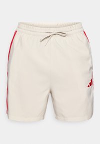 Ανοιχτό μπεζ σορτς με κορδόνι στη μέση και πλευρικές ρίγες σε έντονο κόκκινο. Διαθέτει μικρό κόκκινο λογότυπο στη κάτω δεξιά πλευρά.