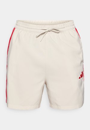 Világos bézs rövidnadrág, húzózsinóros derékrésszel és élénk piros oldalcsíkkal. Kis piros logó található az alsó jobb oldalon.