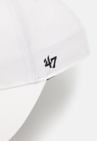Gorra de béisbol blanca con visera curva, tela texturizada y logotipo bordado en negro "47" en el lateral.