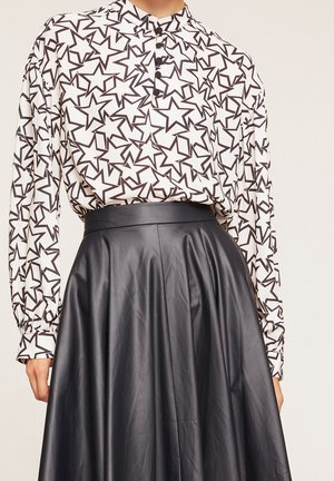 Black star-patterned blouse with buttoned collar, paired with a high-waisted black leather skirt featuring a smooth, flowing design.
