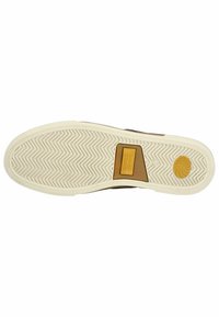 Suela de zapatilla marrón con entresuela de goma blanca, que presenta un diseño de espiga y un logotipo circular amarillo en el talón. Diseño duradero.