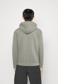 Felpa grigia con cappuccio realizzata in morbido tessuto, con tasca a marsupio e polsini a coste. Design semplice con un aspetto pulito e informale.