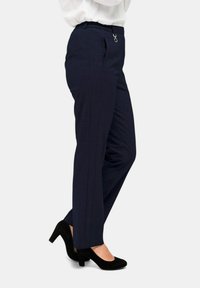 Marineblaue maßgeschneiderte Hose mit strukturiertem Finish, elastischem Taillengummi und silbernen Akzenten. Enganliegendes Design mit geradem Bein.
