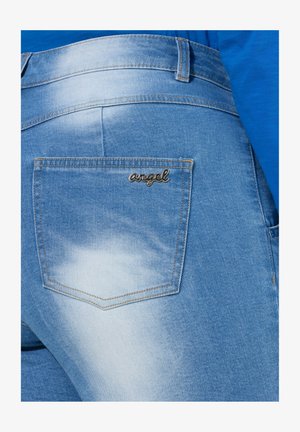 Lichtblauwe denim jeans met een achterzak waarin het geborduurde woord "engel" in cursieve letters is verwerkt en een vervaagde waspatroon.