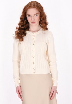 Knit ivory cardigan with a round neckline, button front, two chest pockets, and ribbed hem. Features textured stitch patterns.