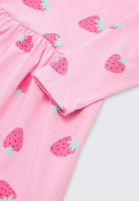 Roze jurk van zachte katoen, met een getailleerde taille en een herhalend patroon van aardbeien in verschillende tinten roze en groen.