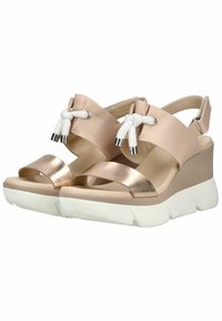Sandales compensées beiges avec semelles blanches épaisses, brides métalliques à l'avant, brides arrière réglables et nœuds en corde blanche sur les brides supérieures.