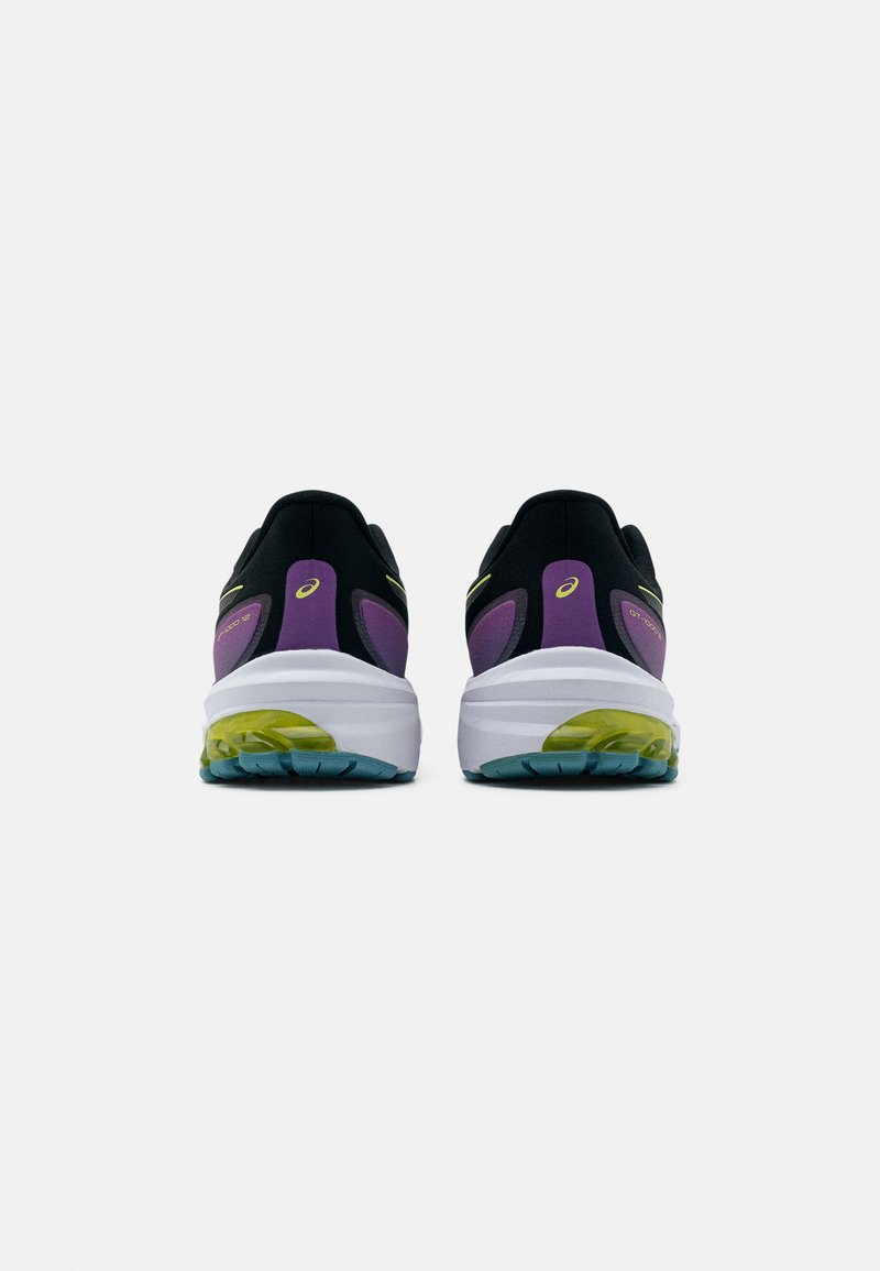 Zapatillas deportivas negras con acentos morados, mediasuela blanca, suela verde y azul, talón acolchado y detalles amarillos en los lados.