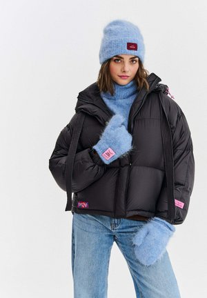 Czarna kurtka puchowa o krótkim kroju, ozdobiona różowymi naszywkami. Jasnoniebieska, puszysta czapka i rękawiczki dopełniają niebieski golf.