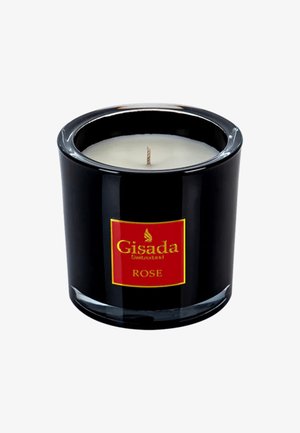 Support en verre noir pour bougie avec une étiquette rouge et dorée portant l'inscription "Gisada Switzerland ROSE." Cire blanche avec une mèche visible. Surface lisse et brillante.