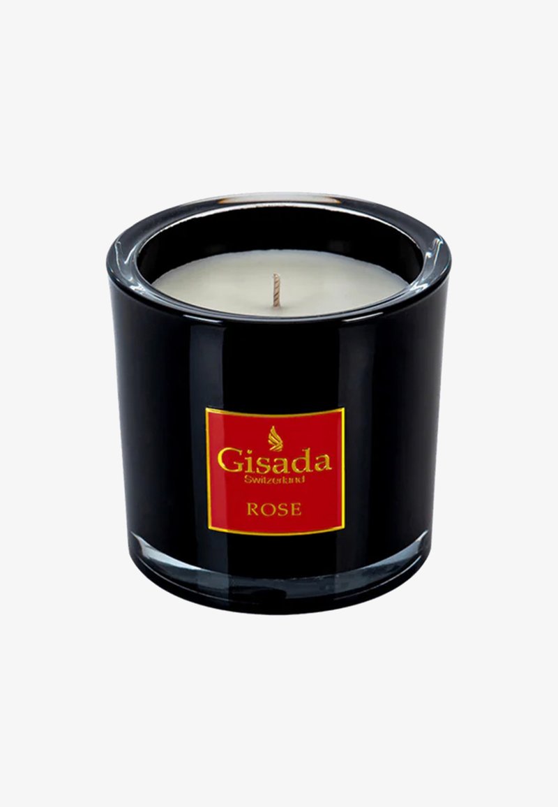 Portavelas de vidrio negro con una etiqueta roja y dorada que dice "Gisada Switzerland ROSE." Cera blanca con una mecha visible. Superficie lisa y brillante.