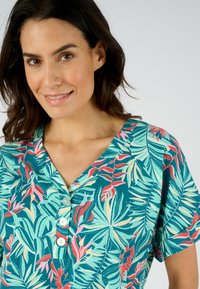 Blusa de manga corta con estampado de hojas tropicales en tonos verde azulado, rojo y verde, con botón en la parte delantera y diseño de escote en V.