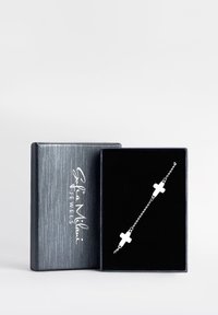 Silberne Kettenarmband mit Kreuzakzenten, präsentiert in einer mit schwarzem Samt ausgekleideten Box mit strukturiertem grauem Äußeren und Markenlogo.