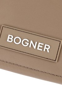 Borsa in nylon khaki con un'etichetta rettangolare in gomma con il testo impresso "BOGNER" in bianco e cuciture visibili lungo i bordi.