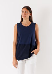 Top senza maniche blu navy con un design a strati, tessuto testurizzato, scollatura rotonda e una tasca sul lato sinistro.