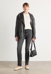 Zwarte leren motorjack, crèmekleurig overhemd, grijze jeans, beige ballerina's en een zwarte handtas. Slim-fit ontwerp met minimalistische accenten.