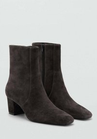 Bottes cheville en daim gris foncé avec un bout pointu et un talon bloc de hauteur moyenne. Dotées d'une fermeture éclair latérale pour un enfilage facile. Texture lisse.
