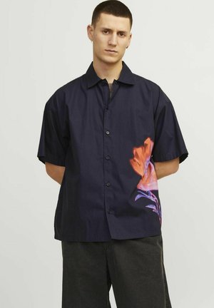 Short-sleeved navy shirt in cotton with a floral print in orange and purple on the left side; features button closure and a relaxed fit.