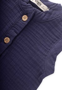 Top de algodón azul marino con una superficie texturizada y acanalada; presenta botones de madera y un escote redondeado, adecuado para bebés de 3 a 6 meses.