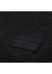 Black corduroy fabric with vertical ridges featuring a rectangular black leather tag embossed with the name "JOHNNY URBAN."