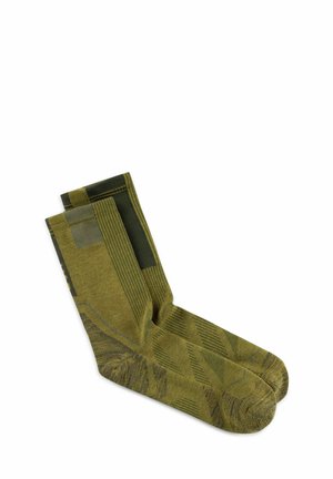 Paar grüne Socken bis zur Mitte der Wade mit geometrischen Mustern und gerippter Textur, flach auf weißem Hintergrund liegend.