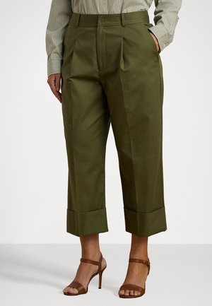 Szerokie, oliwkowozielone spodnie o kroju culotte z podwiniętymi nogawkami, zestawione z brązowymi sandałami na obcasie i pasiastą koszulą z długim rękawem.