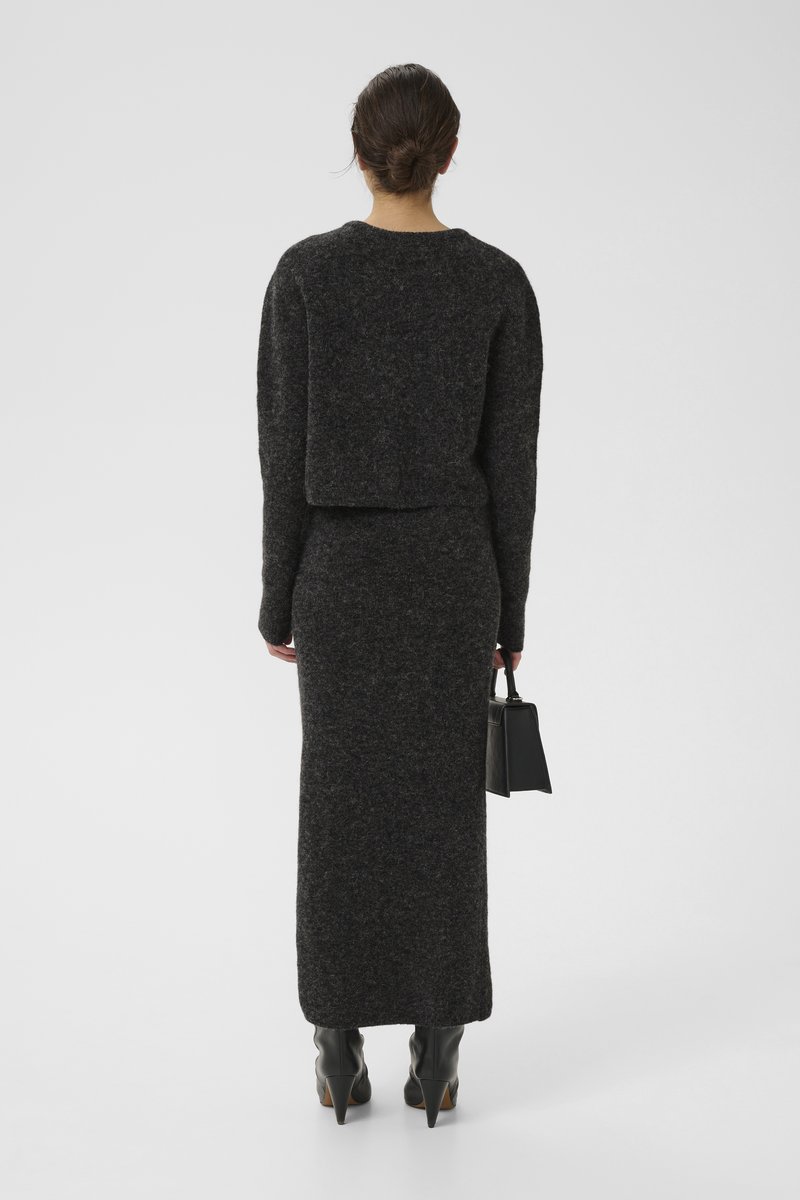 Mørkegrå strikket to-delt sæt bestående af en cropped sweater og en lang nederdel, samlet med en lille sort taske og hælede støvler.