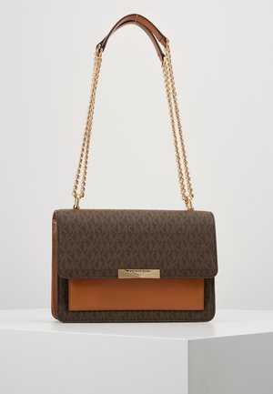 Sac bandoulière en cuir marron monogrammé avec poche avant couleur fauve, bandoulière chaîne dorée et fermoir doré sur un piédestal blanc.