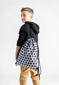 Plecak na sznurki z hexagonalnym czarno-białym wzorem, wykonany z tkaniny, z regulowanymi czarnymi paskami i ściąganym wierzchem.