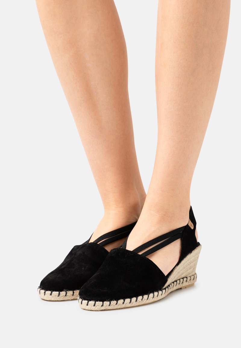 Espadrilles compensées en suédine noire avec un design à lanières croisées, semelle en corde naturelle et couture contrastante.