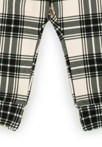 Czarno-białe spodnie w kratę na kremowym tle; wykonane z teksturowanej tkaniny, o prostych nogawkach i gładkim wykończeniu mankietów.
