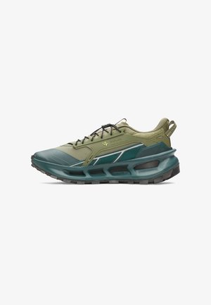 Low-top sportieve schoen in olijfgroen en donker petrol met dikke gevoerde zool, zwarte veters, mesh panelen en merkdetails aan de zijkant en hieltab.