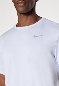 Világoskék Nike póló, rövid ujjal, kerek nyakkal, textúrált anyagból, bal mellkason egy kis szürke Nike logóval.