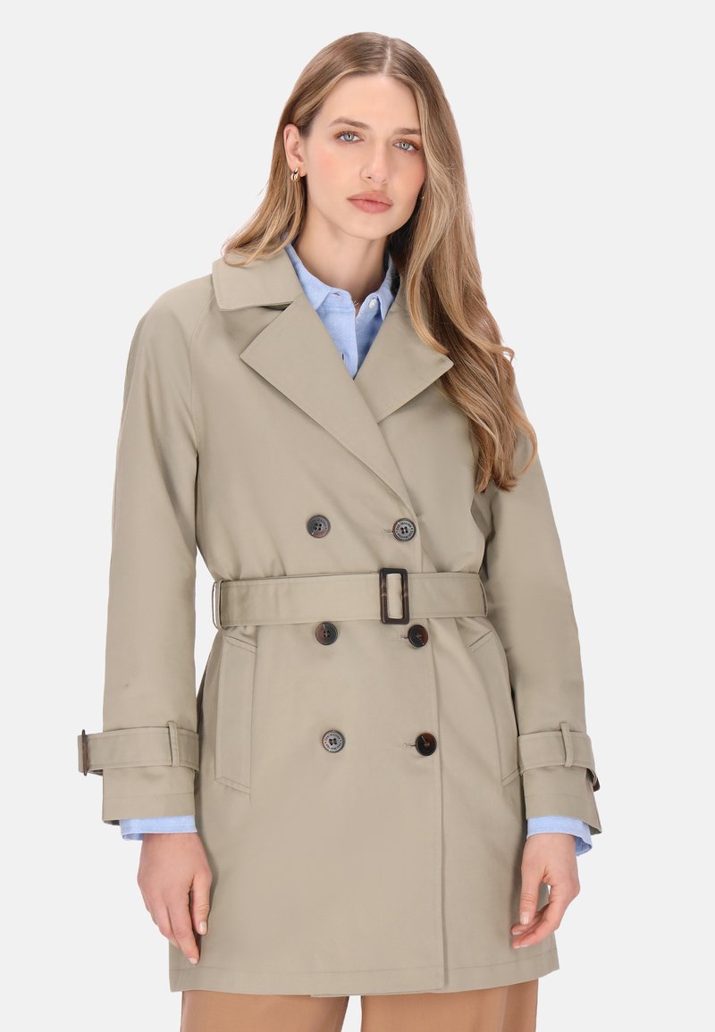 Abrigo trench beige con diseño de doble botonadura, cuello grande, cinturón en la cintura y detalles de botones. Hecho de un material liso y resistente al agua.