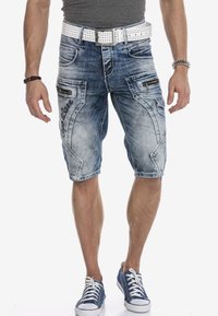 Leren spijkerbroekshorts in lichtblauw met vervaagde delen, met meerdere ritszakken en een geborduurd logo. Witte riem met studs.