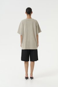 Oversized gray t-shirt with short sleeves, paired with loose black shorts. Smooth texture, simple design, and neutral colors.