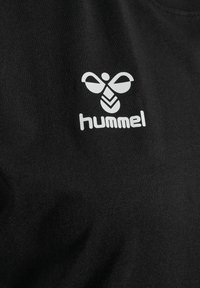 Zwart T-shirt met een witte "hummel"-logo en een gestileerd bijenontwerp. De stof oogt glad met een zachte textuur.