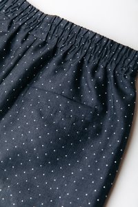 Temno modri kratki hlači z belimi pikami, nabranim elastičnim pasom in majhnim zadnjim žepom. Material izgleda mehak in teksturiran.