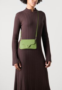 Borsa a tracolla verde in pelle con finitura testurizzata, dotata di chiusura a patta arrotondata, tracolla regolabile e accenti in metallo.