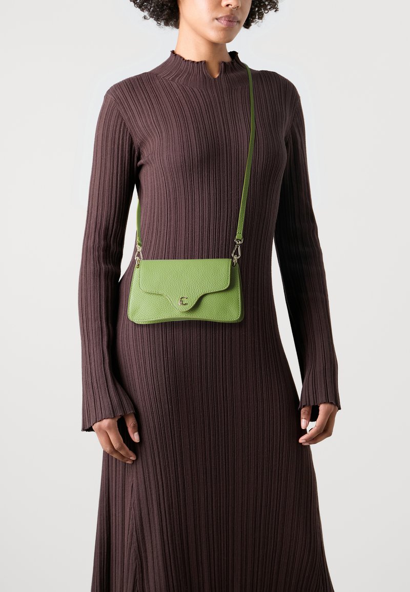 Grønn lærcrossbody-veske med teksturert finish, rund klaffelukking, justerbar stropp og metalldetaljer.