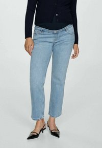 Lichtblauwe denimjeans met een recht model, voorzien van een vijf-pocket ontwerp en subtiele stiksels. Gecombineerd met zwarte hakschoenen.