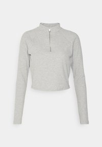 Top corto grigio chiaro a maniche lunghe con colletto alto e zip corta frontale.