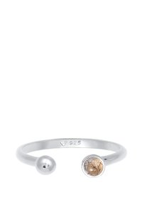 Silberner verstellbarer Ring mit einem dünnen Band, der auf einer Seite einen runden Stein mit goldenen Einschlüssen und auf der anderen Seite eine glatte, kugelförmige Endung hat.