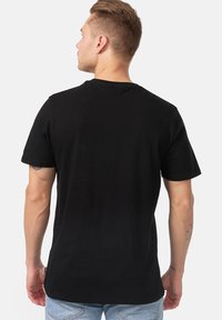 Tricou din bumbac negru cu un gât clasic, mâneci scurte și o croială lejeră. Textură netedă cu un design simplu.