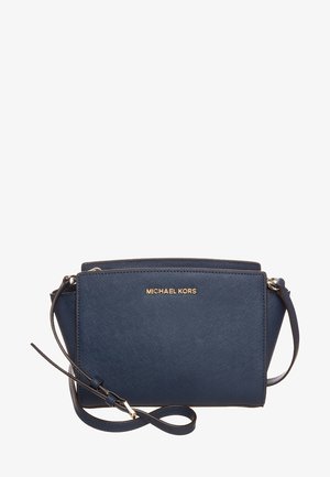 Granatowa torebka na ramię Michael Kors z złotym logo, teksturowanym wykończeniem i regulowanym paskiem na białym tle.