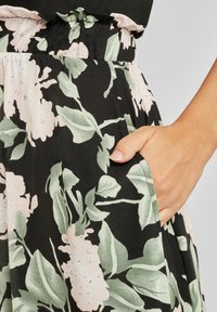 Hame frak dengan cetakan floral yang menampilkan latar belakang hitam, bunga merah muda muda, dan daun hijau; dilengkapi dengan pinggang elastis dan saku samping.