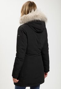 Czarna ocieplana kurtka z futrzanym wykończeniem w kapturze, dopasowany fason z akcentem w talii oraz bezszwowym wykończeniem pleców.