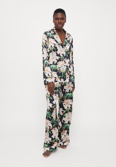 Floral pajama set featuring black fabric, long sleeves, lapel collar, and white lilies with green leaves. Loose-fitting pants with matching pattern.